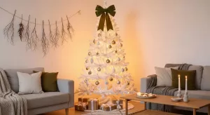 Decoração de Natal 2025 minimalista com árvore branca, laço gigante verde e iluminação LED âmbar em sala aconchegante
